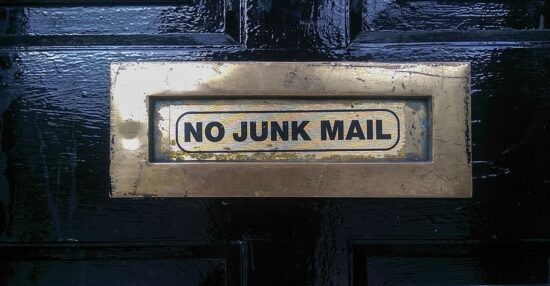 Siyah bir kapıdaki metal posta kutusunun üzerinde, spam mail engellemeyi simgeleyen "NO JUNK MAIL" (İstenmeyen Posta Yok) uyarısı bulunuyor.