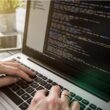 Bir yazılım geliştirici, en iyi kod editörü programlarından birini kullanarak dizüstü bilgisayarında kod yazıyor. Ekranda, bir IDE arayüzünde renklerle vurgulanmış CSS kod satırları görünüyor.
